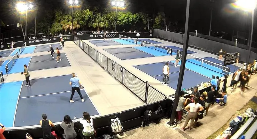 Packed pickleball courts under the lights at night at Dink Club