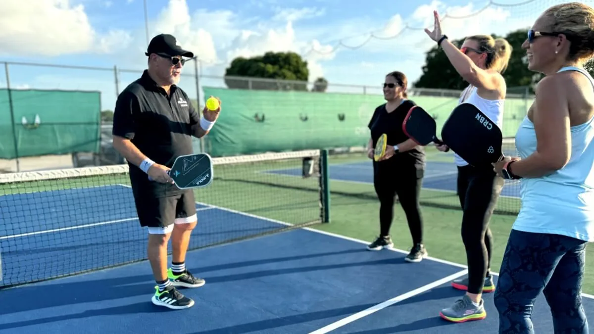Players and a coach enjoying a clinic on the outdoor courts at Dink Club in Miami